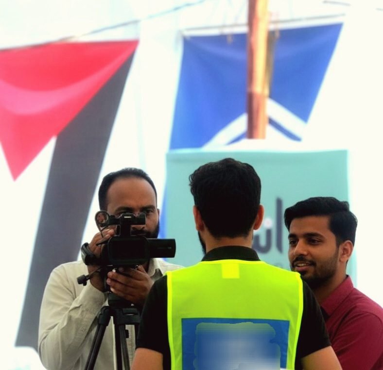 Zaid Ali giving a media interview during Alkhidmat Foundation’s Gaza Relief & Ration Packing Drive in Karachi. Zaid Ali giving media interview as humanitarian volunteer during Alkhidmat Foundation Gaza relief ration packing drive Karachi Pakistan